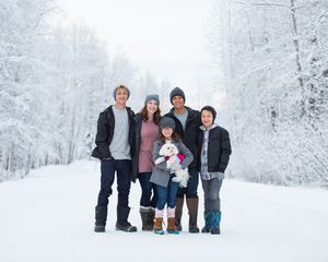 Family enjoys a winter wonderland together in snow covered forest during outdoor photo session.