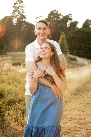 A couple shares a romantic moment in a sunlit meadow during golden hour.