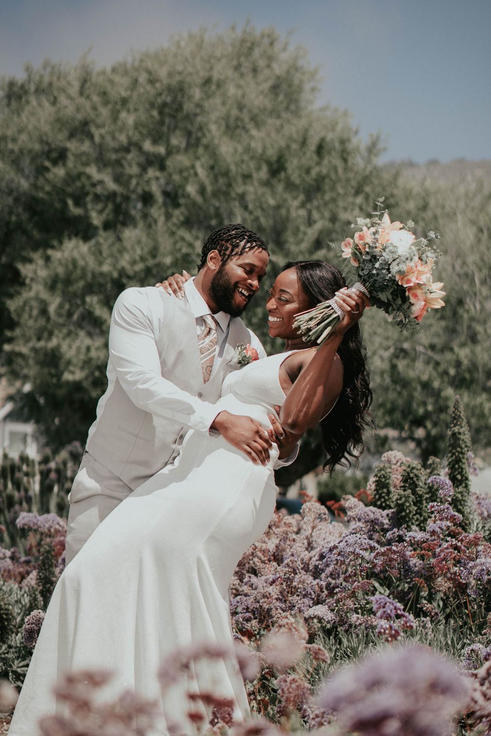 Couple in wedding attire sharing romantic moment among flowering garden.
