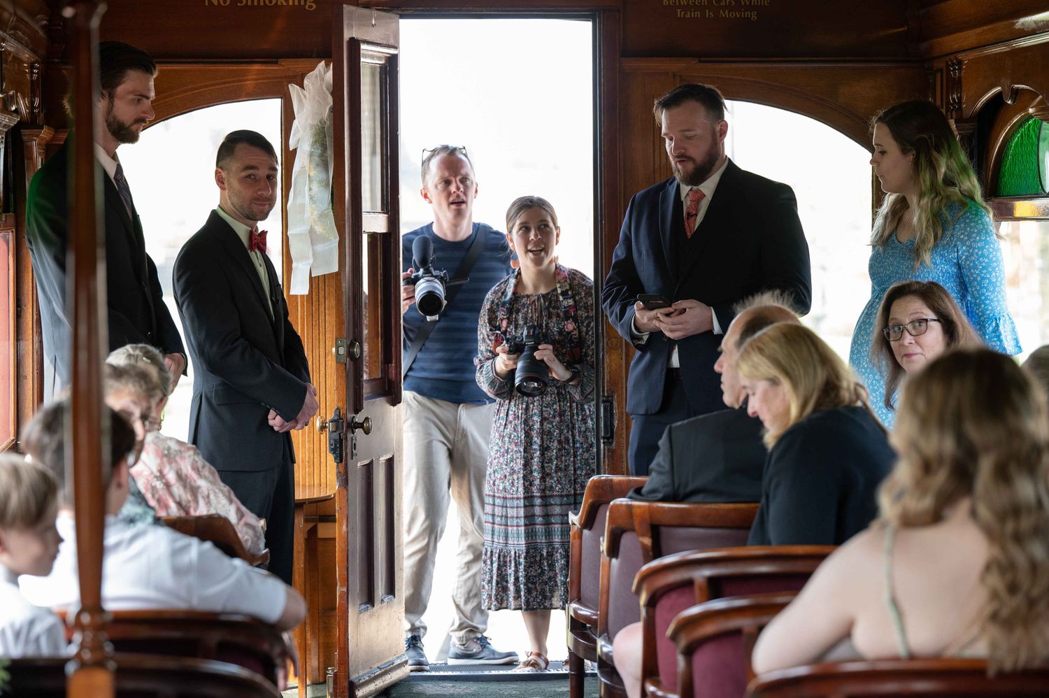 Wedding party gathering inside a vintage trolley car during transportation.