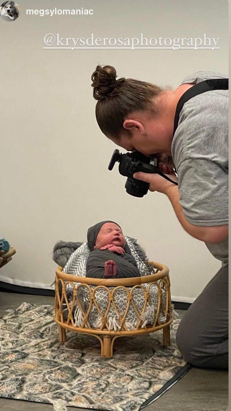 Photographer taking picture of newborn baby in woven basket during professional photo session.