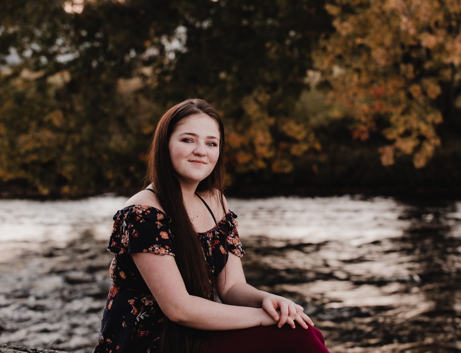 A fall portrait session with autumn leaves and golden sunlight in the background.