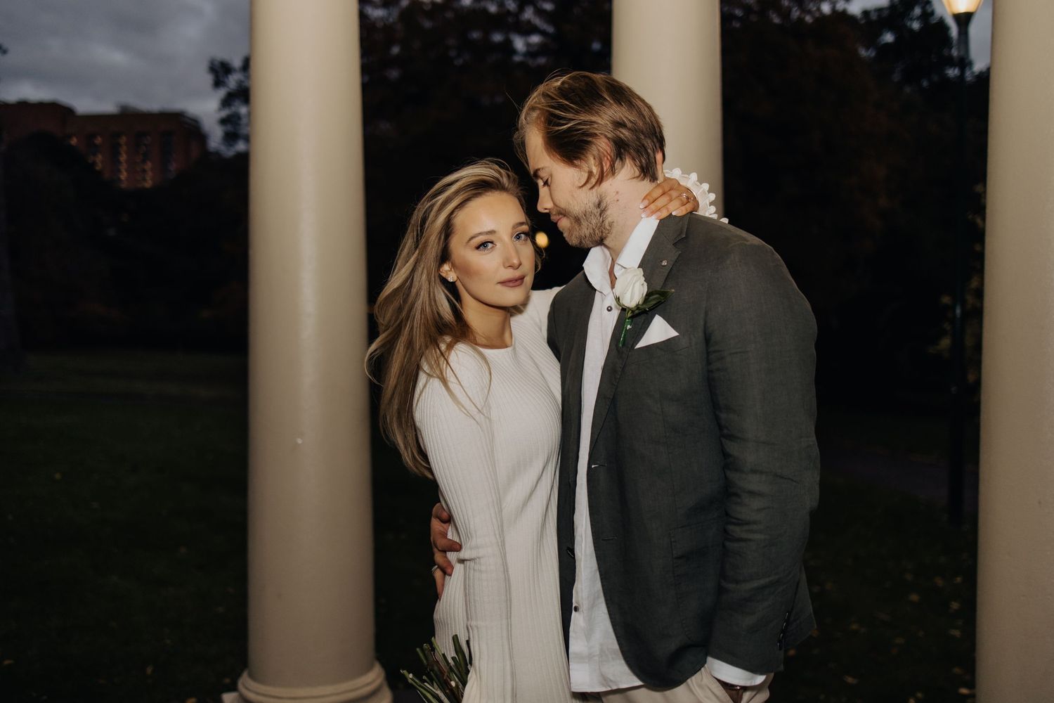 Romantic wedding portraits captured between elegant white columns at dusk.