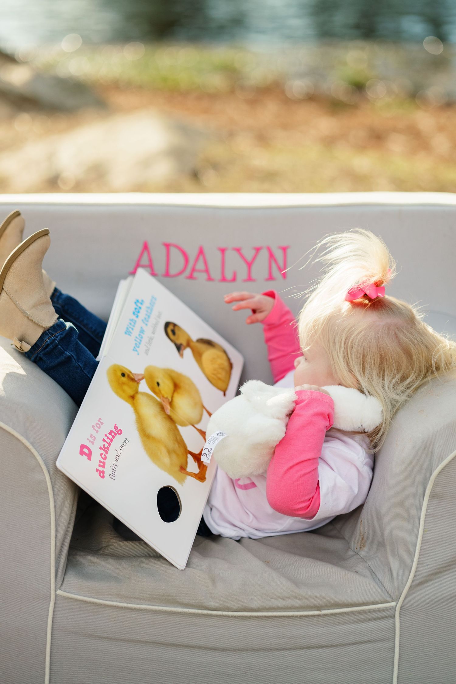 Baby doll lying on chair with personalized book reading 'Adalyn' in pink text.