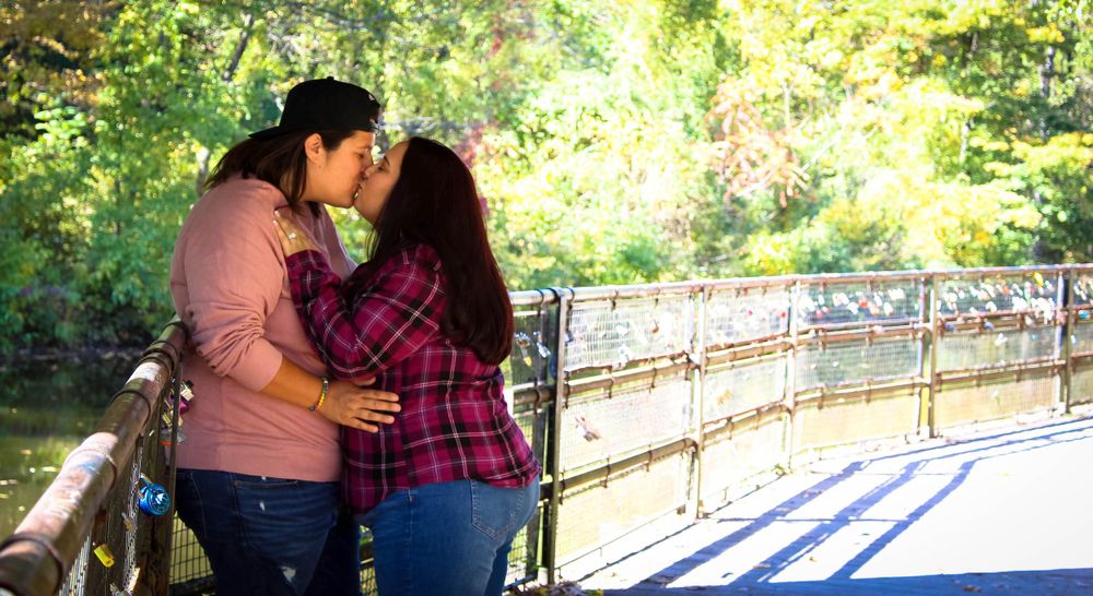 Romantic couple sharing a tender moment on a bridge surrounded by autumn foliage.