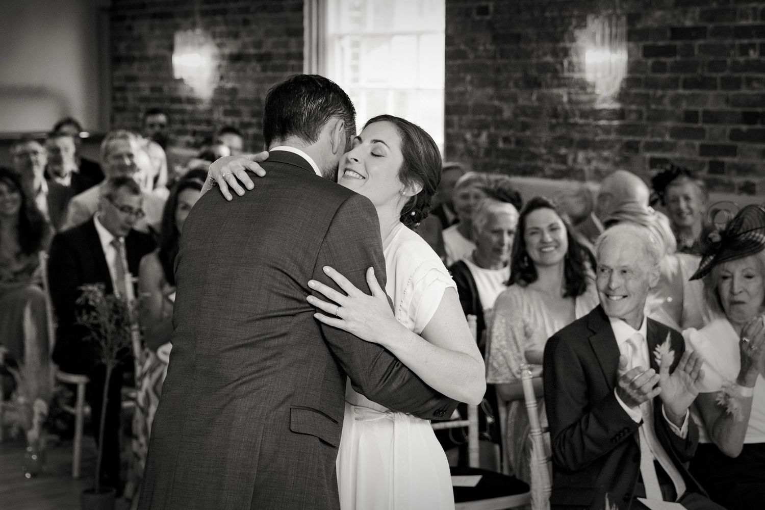 Black and white photo of newlyweds embracing during first dance.