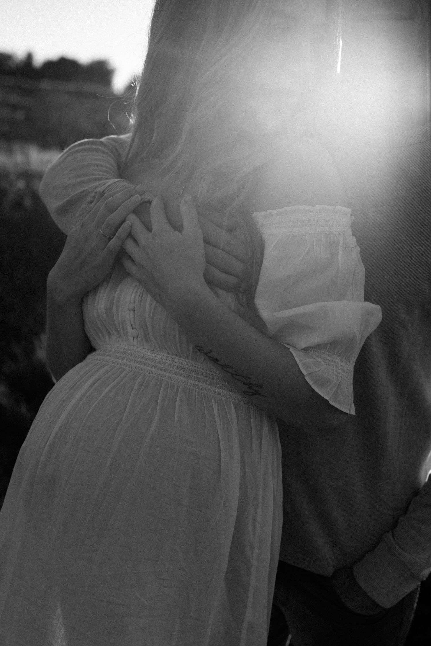 Pregnant mama is embraced by husband during maternity photoshoot in San Diego.