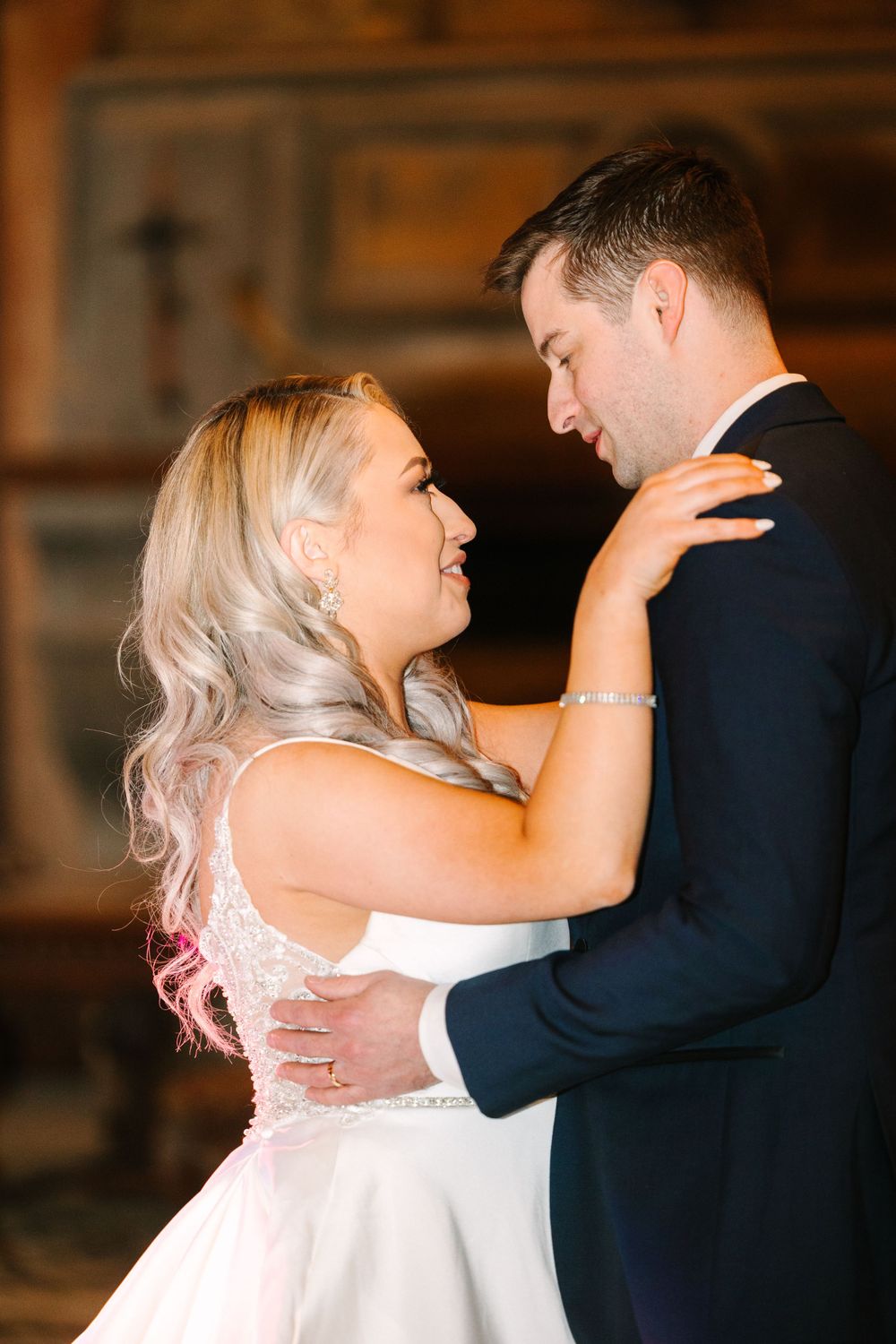 An intimate dance moment captured indoors showing elegant wedding attire and warm lighting.