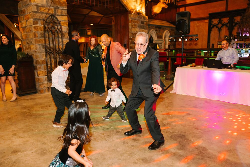 Wedding reception guests dancing joyfully on the dance floor in a rustic venue.