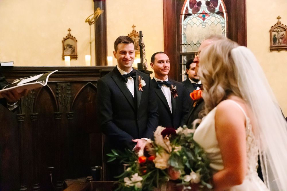 Wedding ceremony taking place in historic church with wooden pews.