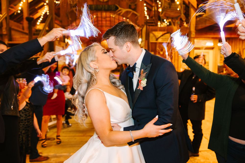 Romantic reception moment with sparklers creating a magical atmosphere in a rustic barn venue.