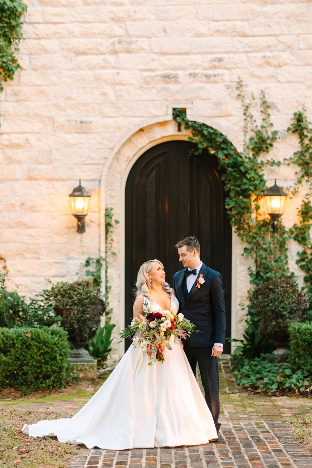 Romantic bridal portrait in front of stone archway with glowing lanterns and ivy.