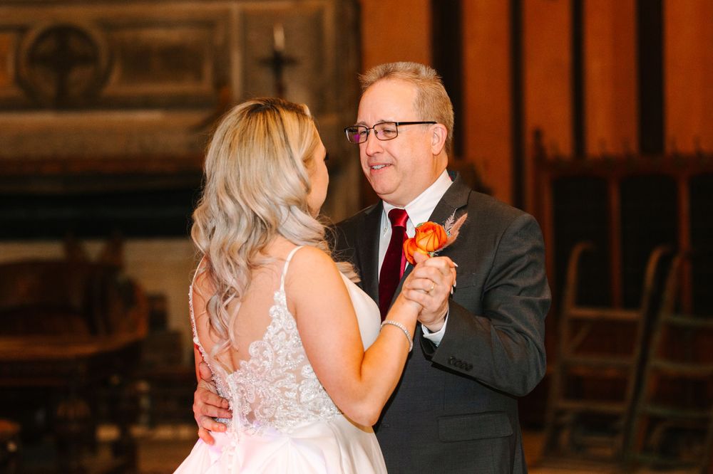 A heartwarming dance captured indoors with warm lighting and elegant formal attire.