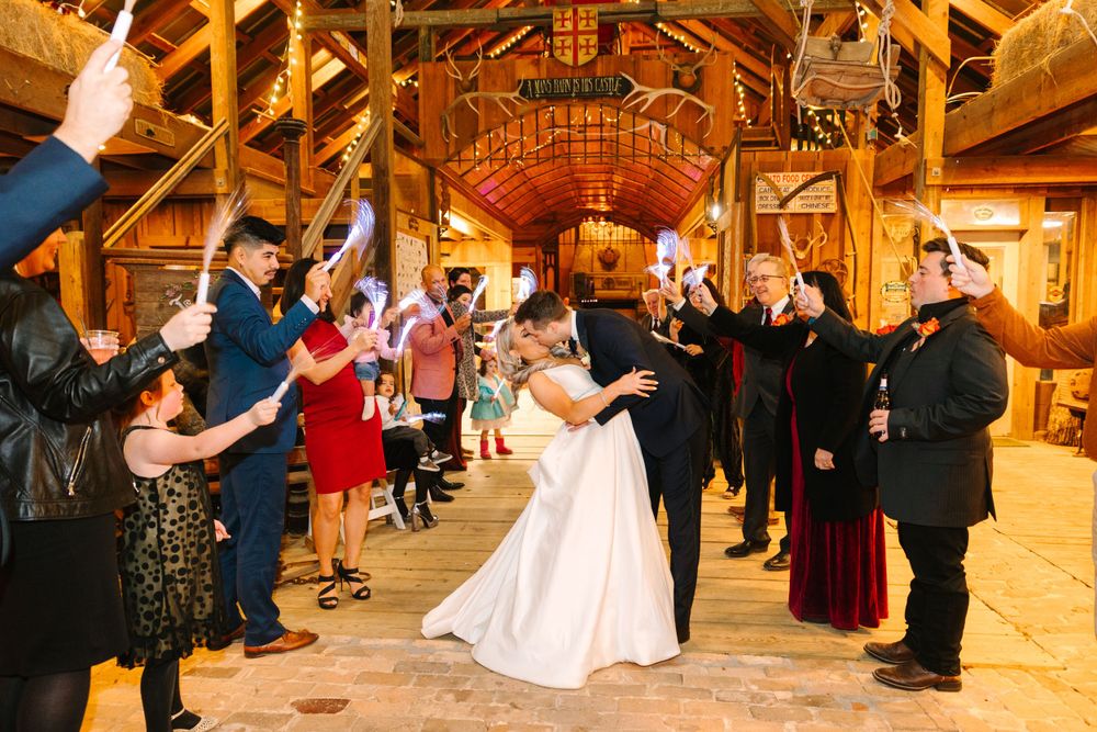 Wedding celebration in a rustic barn venue with guests forming an aisle for the newlyweds.