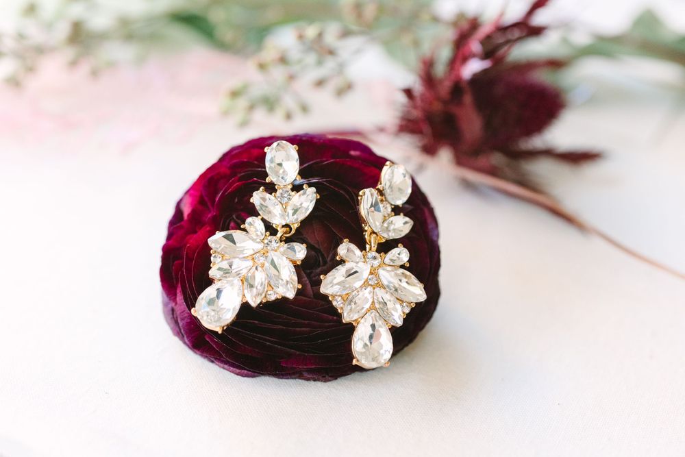 Crystal bridal earrings displayed on dark burgundy velvet surface.