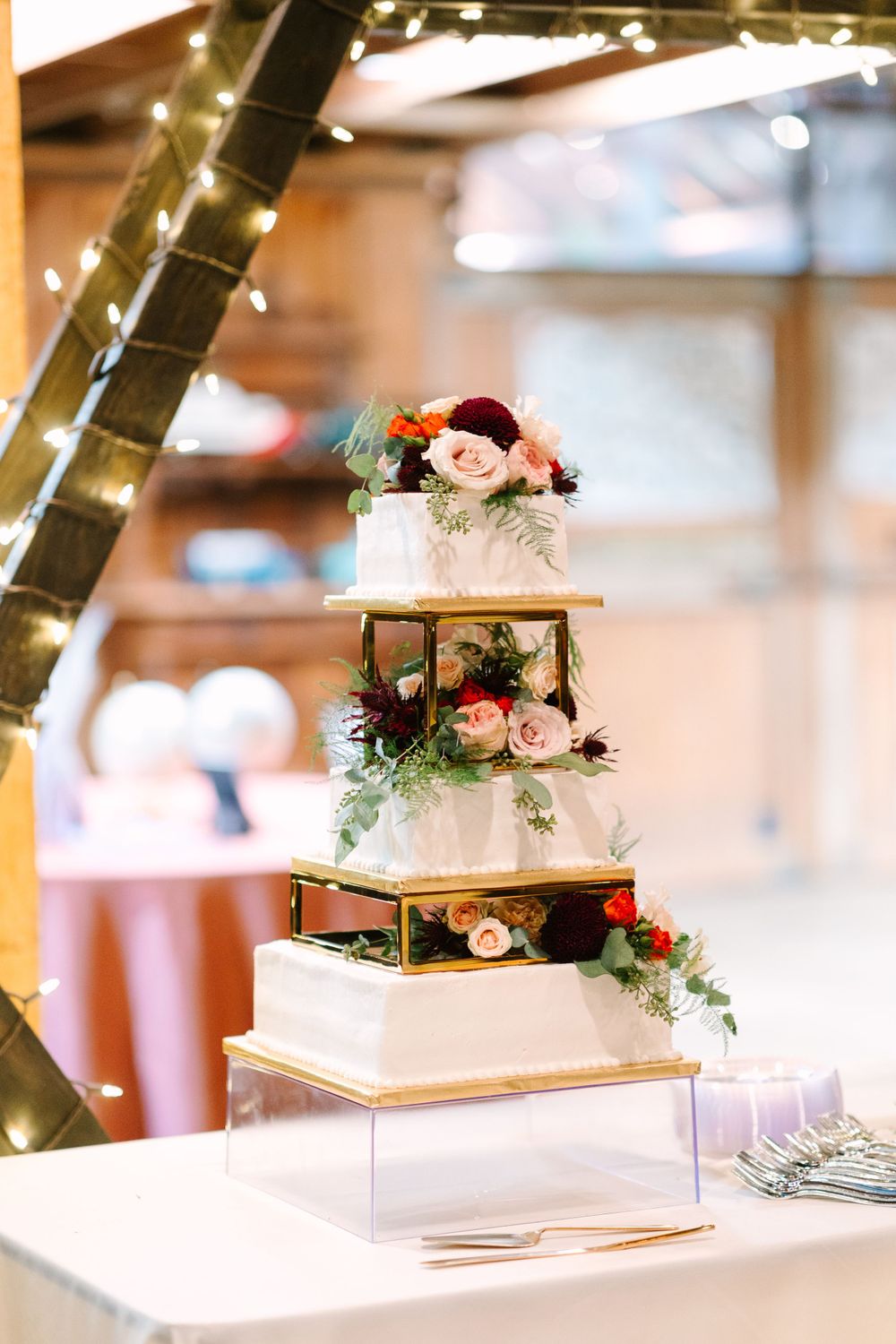Elegant three-tier white wedding cake with floral decorations and gold metallic separators.