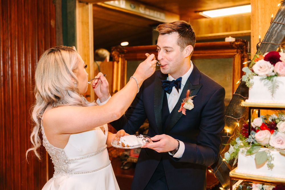 Wedding couple playfully shares cake during reception festivities.