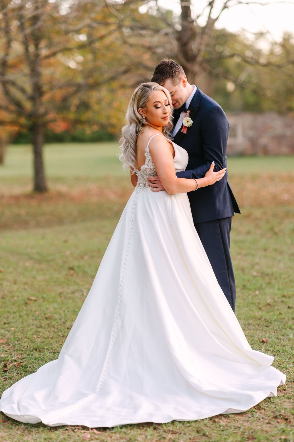 A tender moment between newlyweds against an autumn backdrop with a flowing white wedding gown.