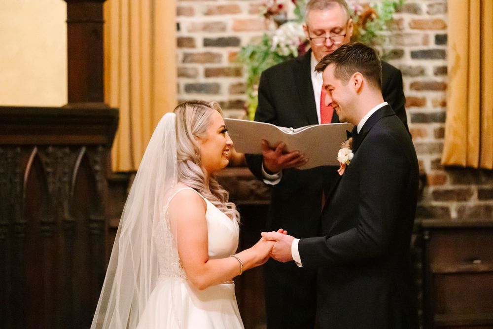 An intimate wedding ceremony moment in front of a brick wall with a decorative cross.