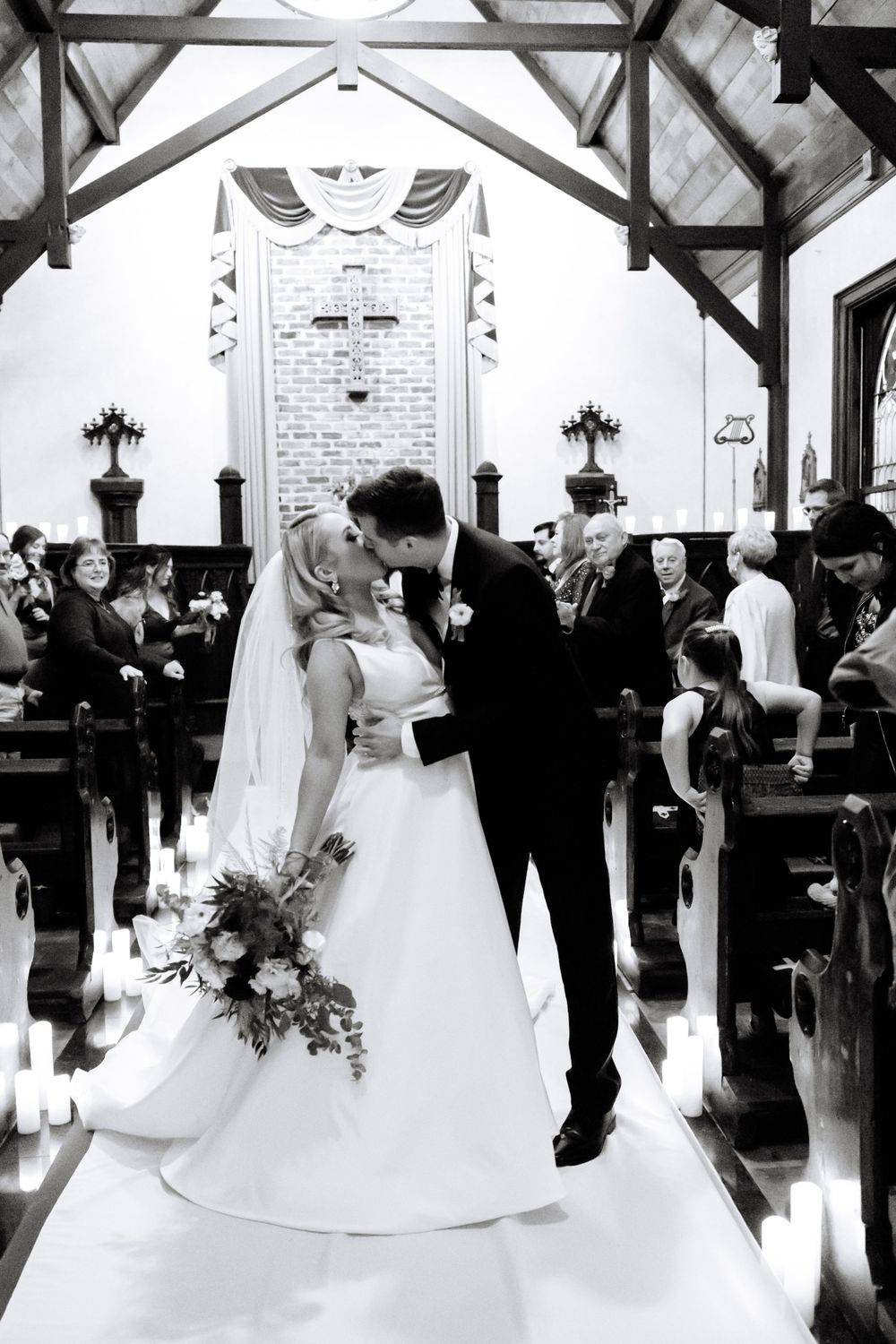 Wedding couple shares intimate moment at altar in elegant black and white church ceremony.
