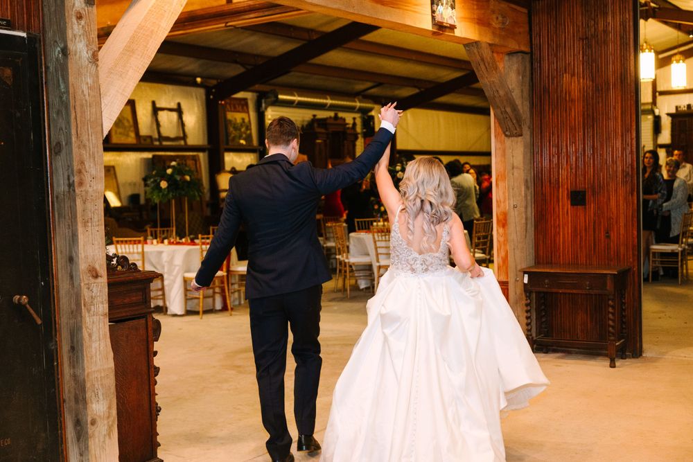 Newlyweds dance together in rustic wooden reception venue.