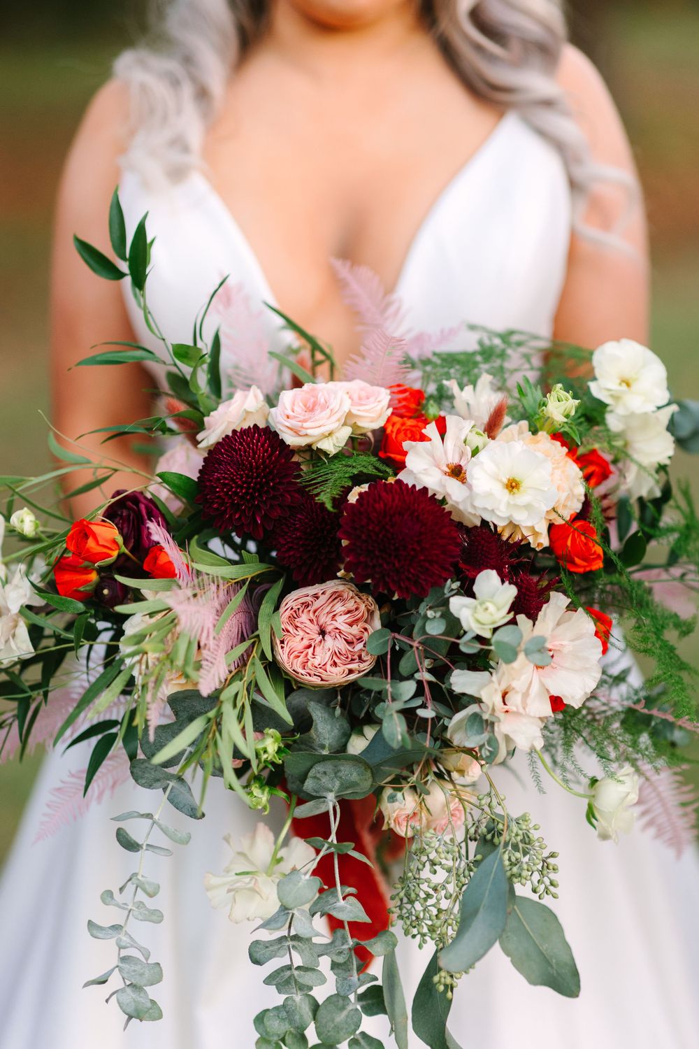 Lush bridal bouquet with burgundy dahlias, pink roses, and cascading greenery.