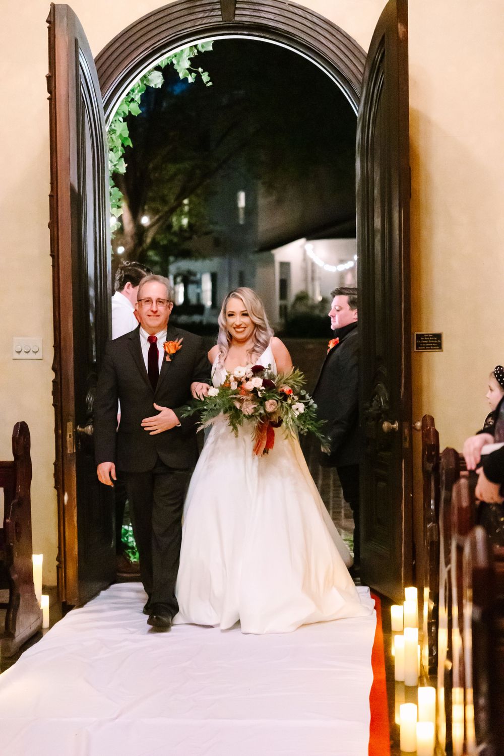 Traditional wedding ceremony processional in church with candlelit aisle.
