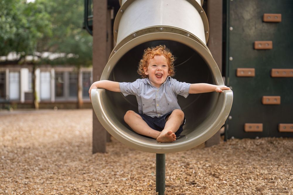 toddler boy sitting on playground slide in Landa Gardens at Landa Library San Antonio Texas