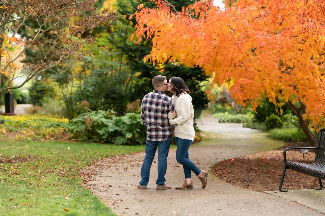 Couple walks along autumn path with vibrant orange and red fall foliage.