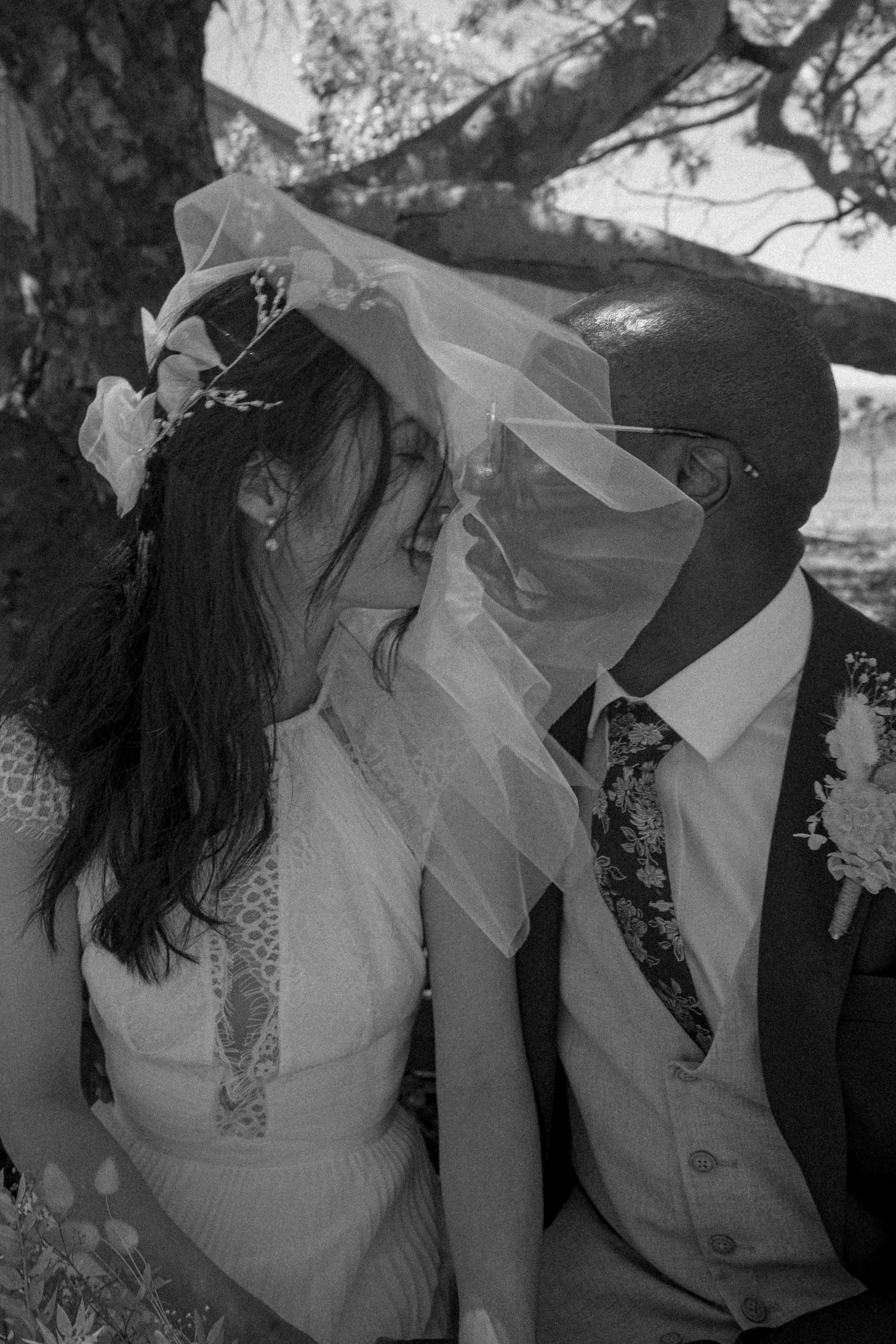 Black and white romantic wedding photos showing intimate moments with flowing veil and elegant dress details.