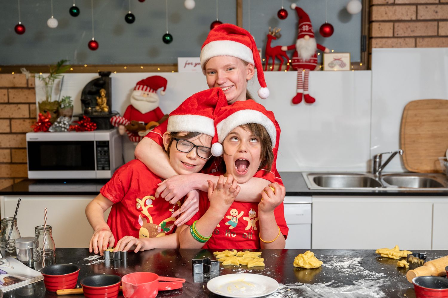 Three kids being silly at Christmas time in the kitchen
