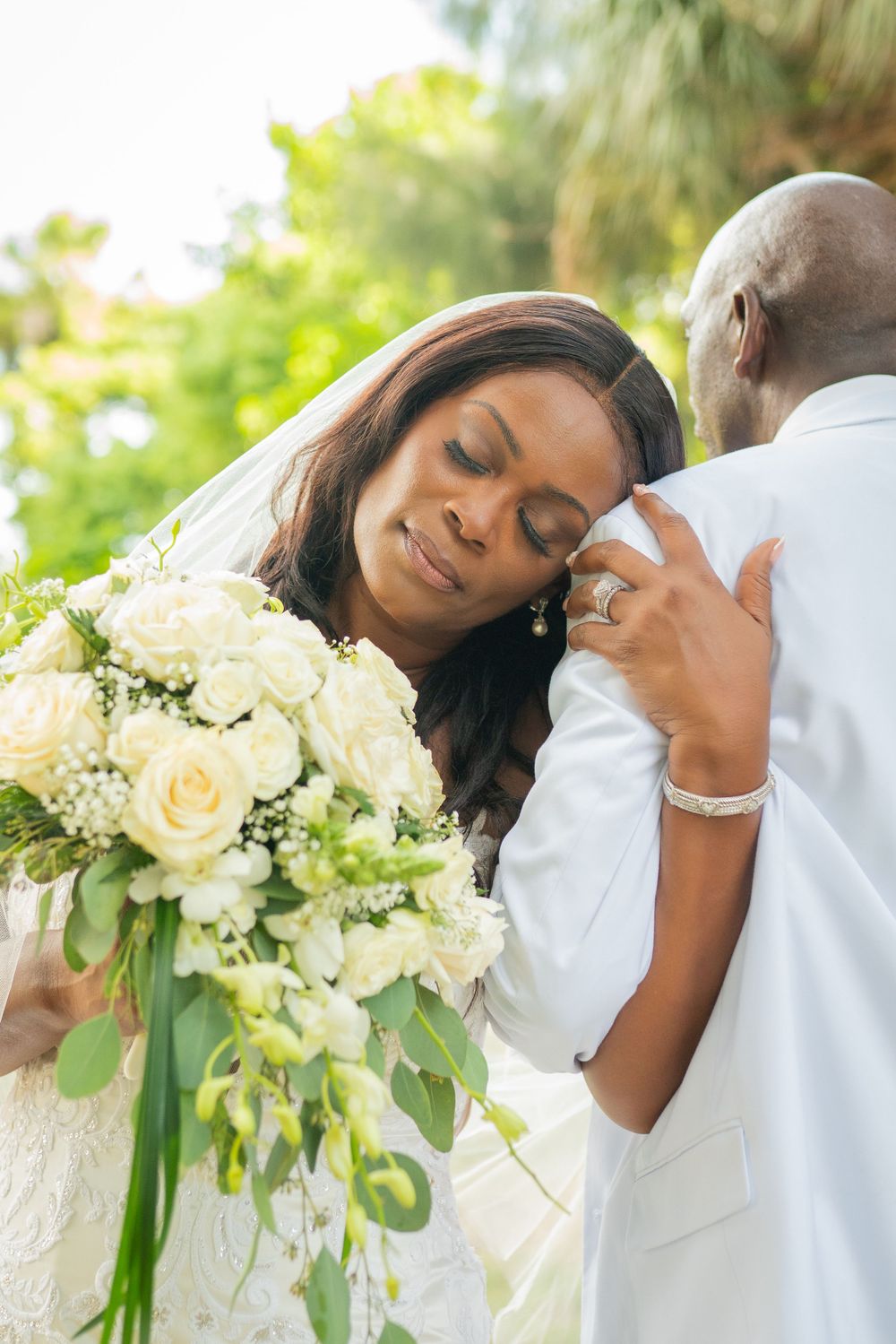 Tender moment between newlyweds with white rose bouquet.