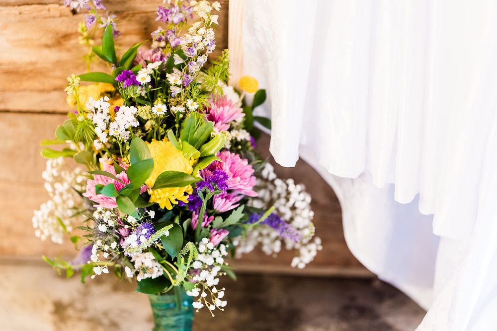 Vibrant wedding bouquet with sunflowers, pink flowers and baby's breath against a rustic wooden backdrop.