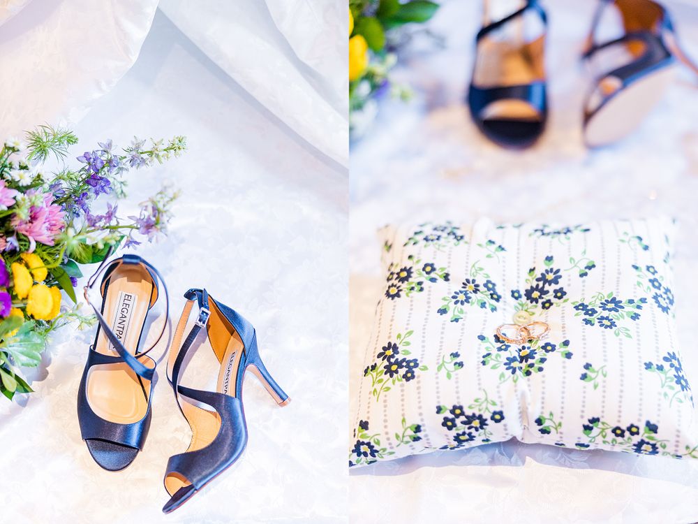 Navy blue wedding heels styled with colorful flowers and a floral patterned pillow.