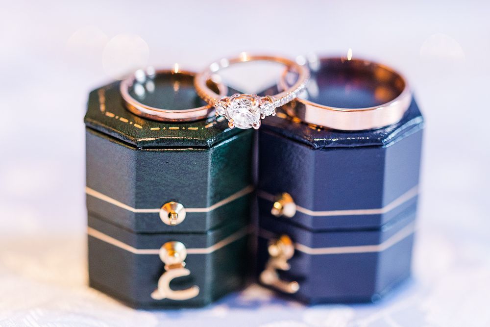 Diamond engagement ring displayed on dark blue octagonal ring boxes with gold accents.