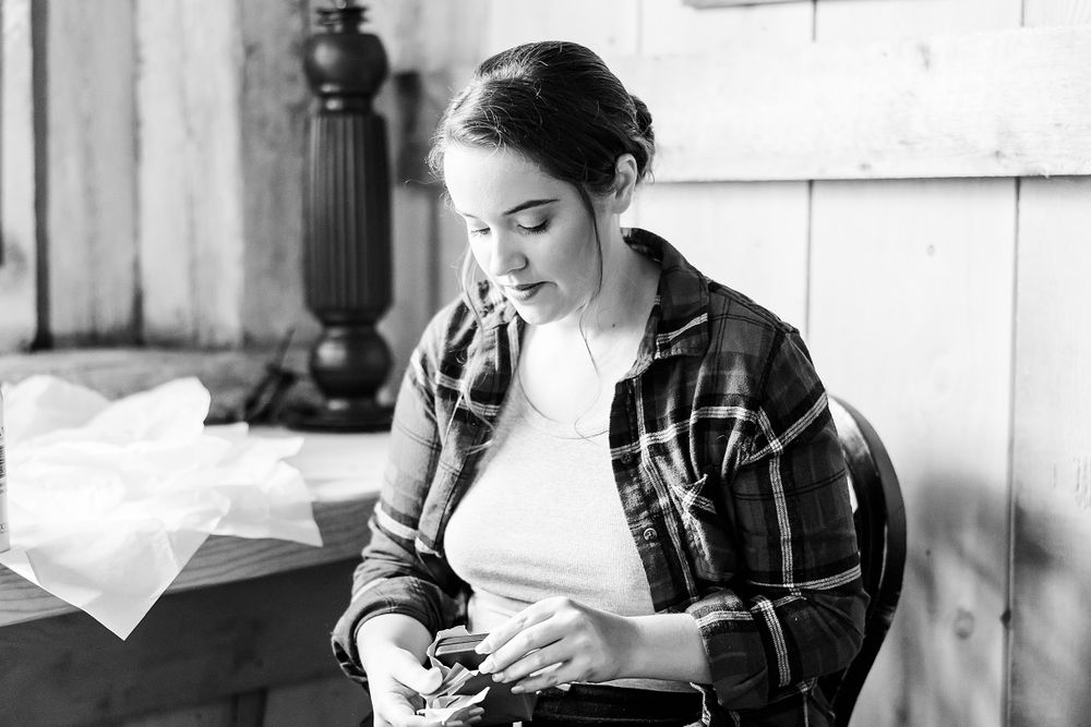 Black and white portrait showing someone writing at a desk in a plaid shirt.