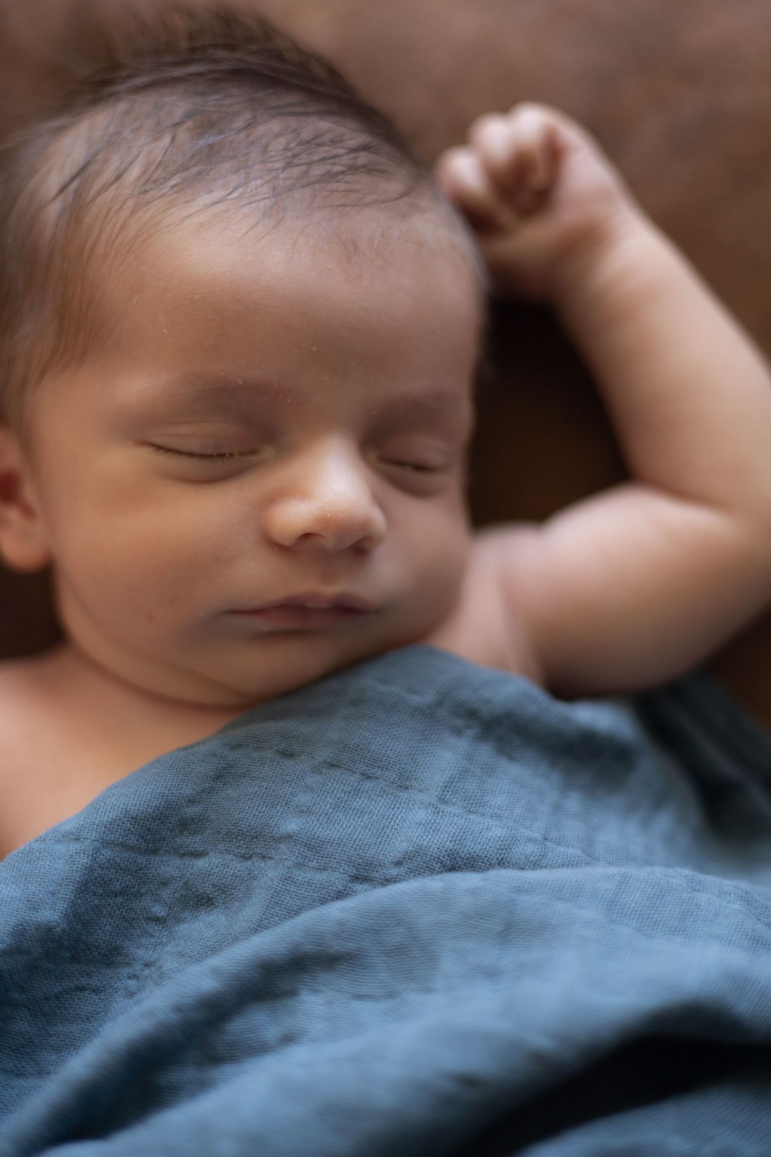 Peaceful sleeping newborn resting on blue blanket in soft lighting.