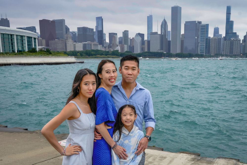 A family poses along Chicago's waterfront with the iconic skyline visible across Lake Michigan.