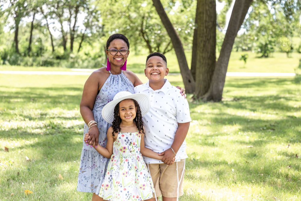 A cheerful summer family portrait captured in a sunny park setting.
