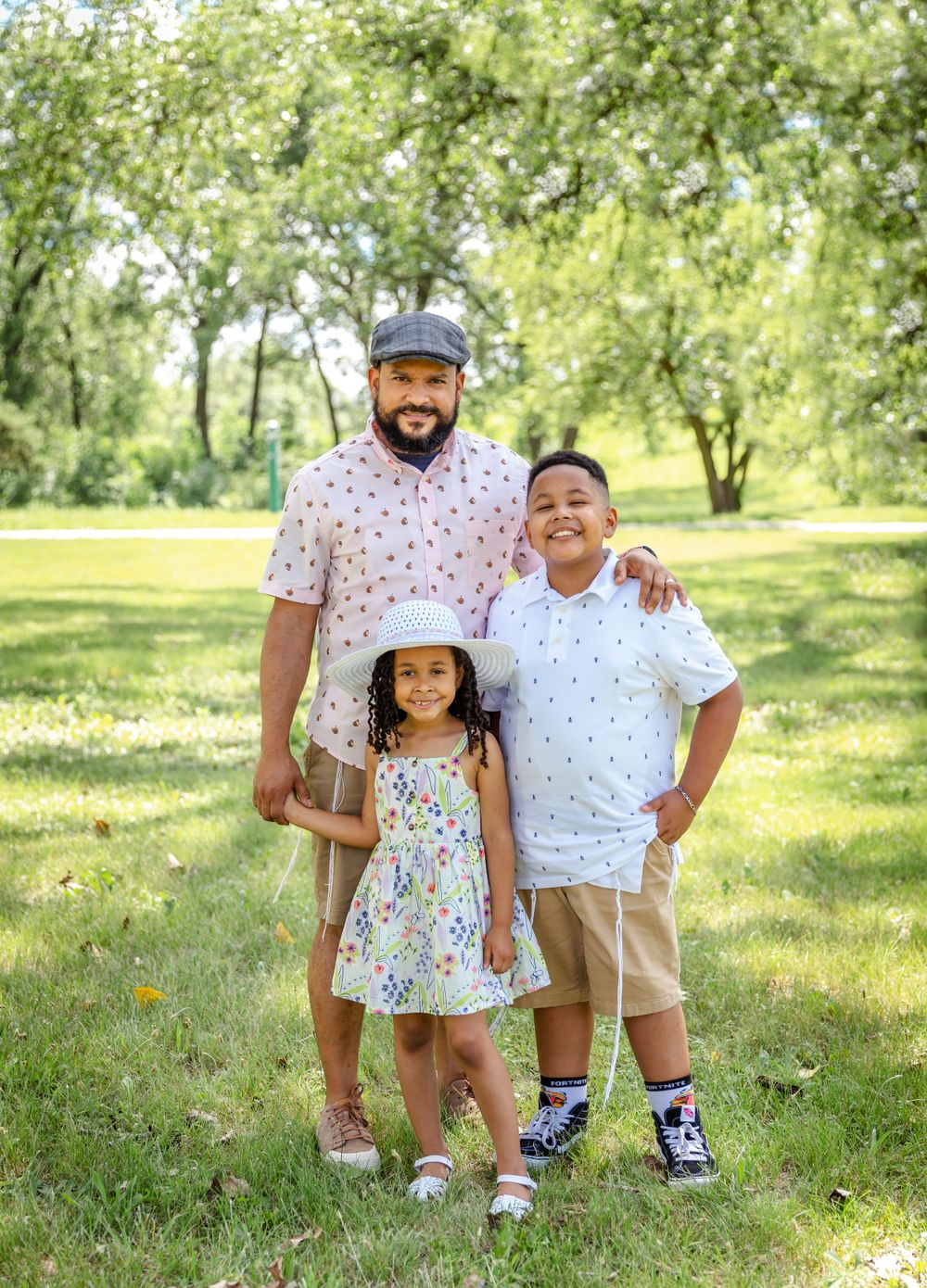 A sunny outdoor family portrait among blooming trees in a park.