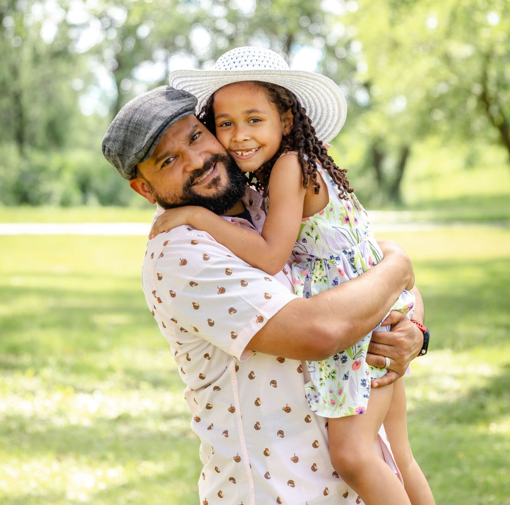 A joyful outdoor portrait in a park with sunlit trees in the background.