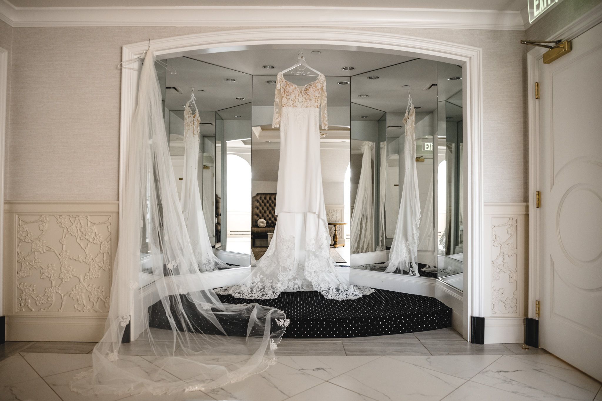Multiple wedding dresses displayed elegantly in a mirrored bridal boutique.