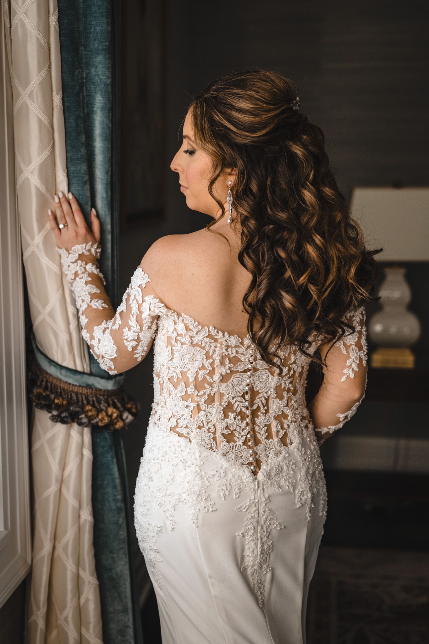 Close-up details of delicate lace wedding dress with sheer sleeves and intricate embroidery.