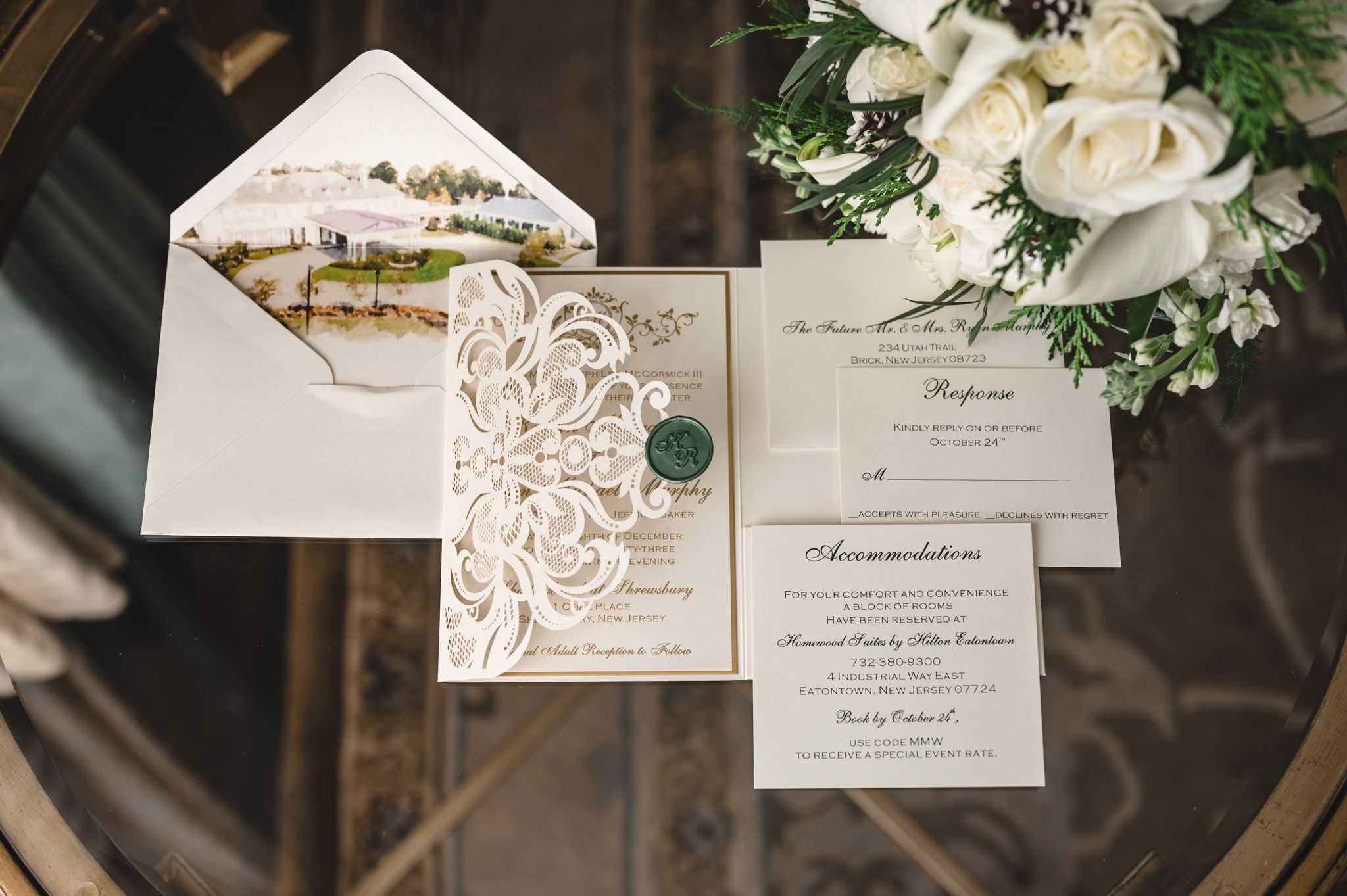 Elegant wedding invitation suite with white floral details and calligraphy on textured paper.