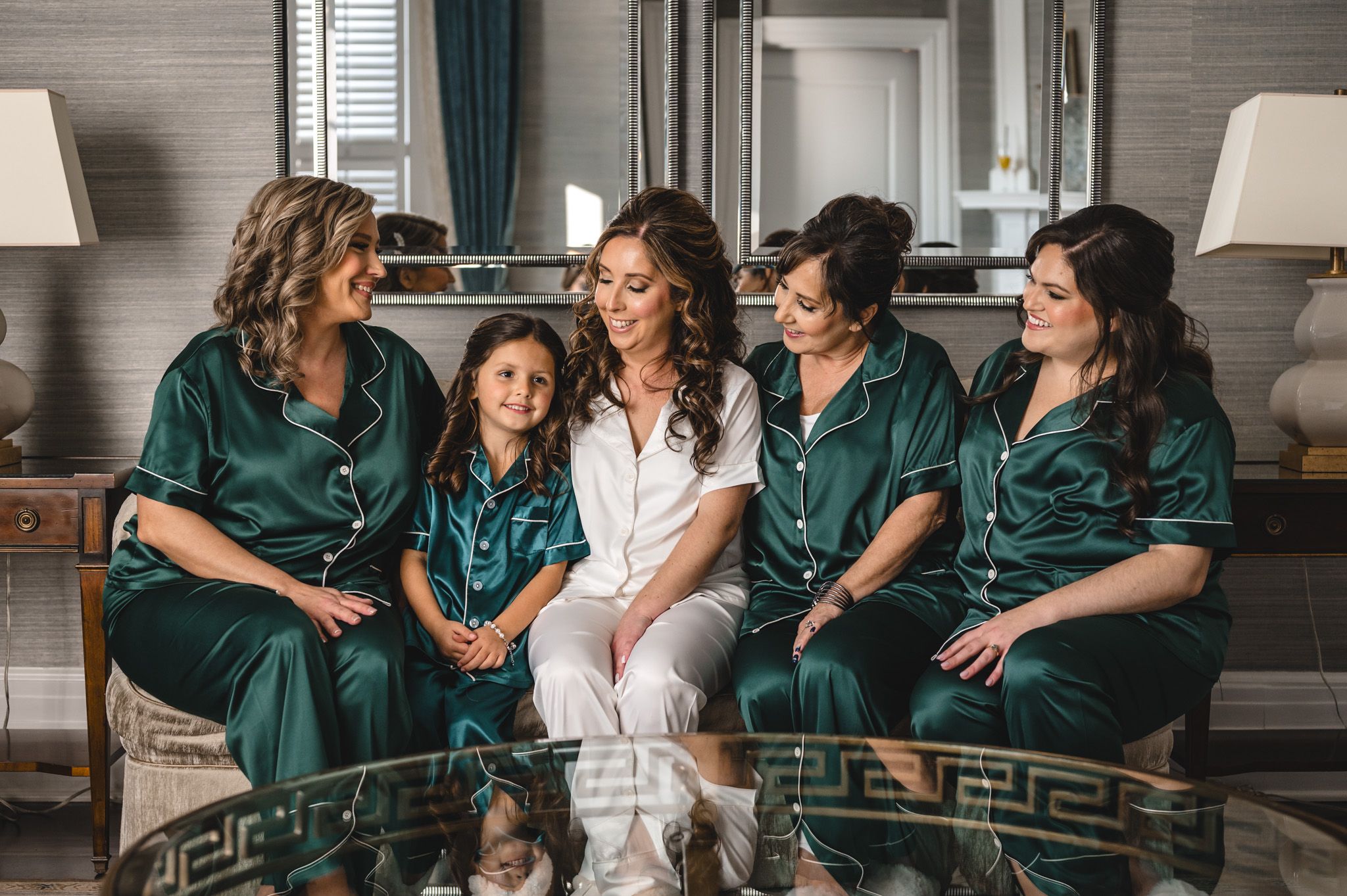 Wedding party in emerald green robes lounging together on a bed.