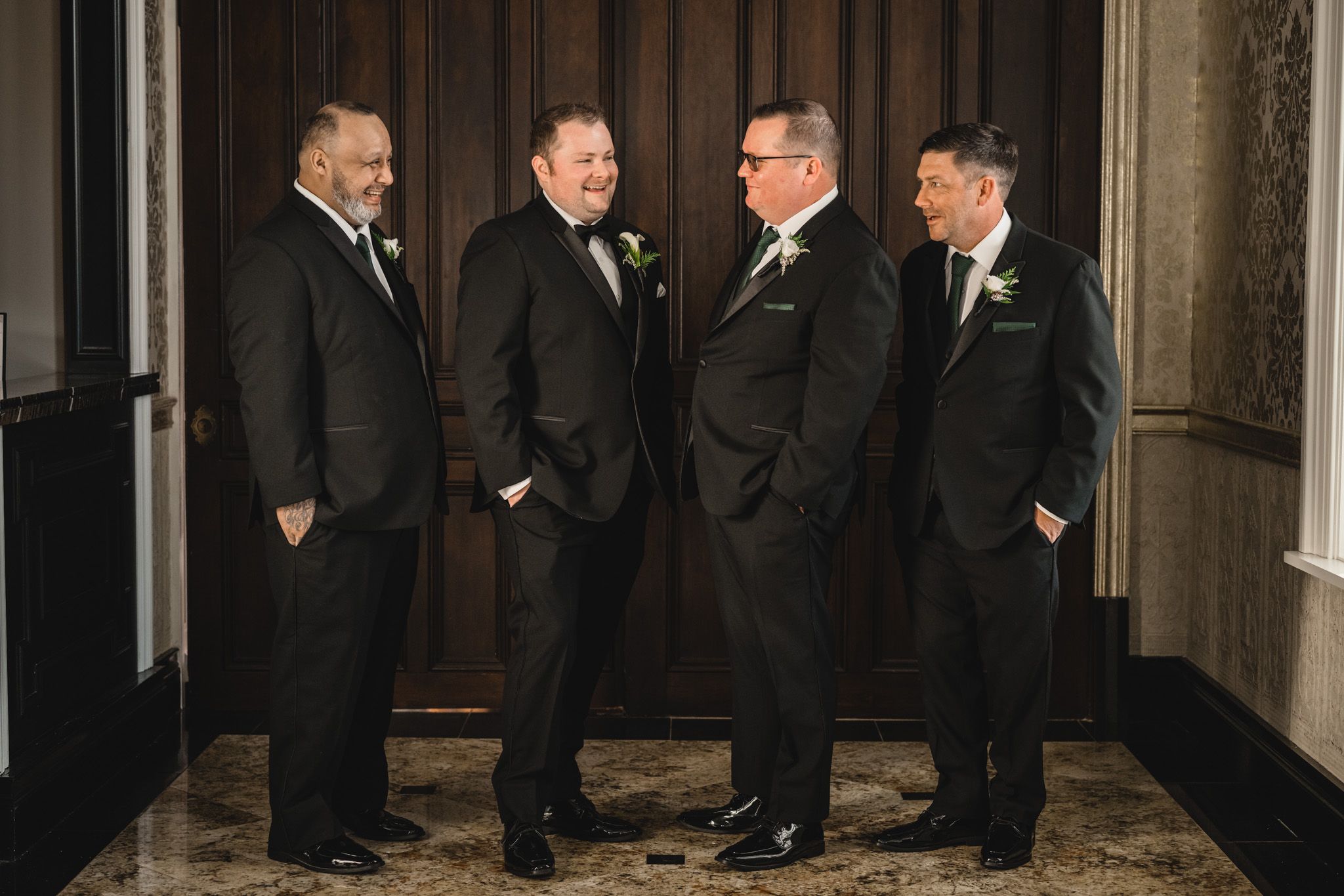 A group in formal black tuxedos gather for a wedding party photo.