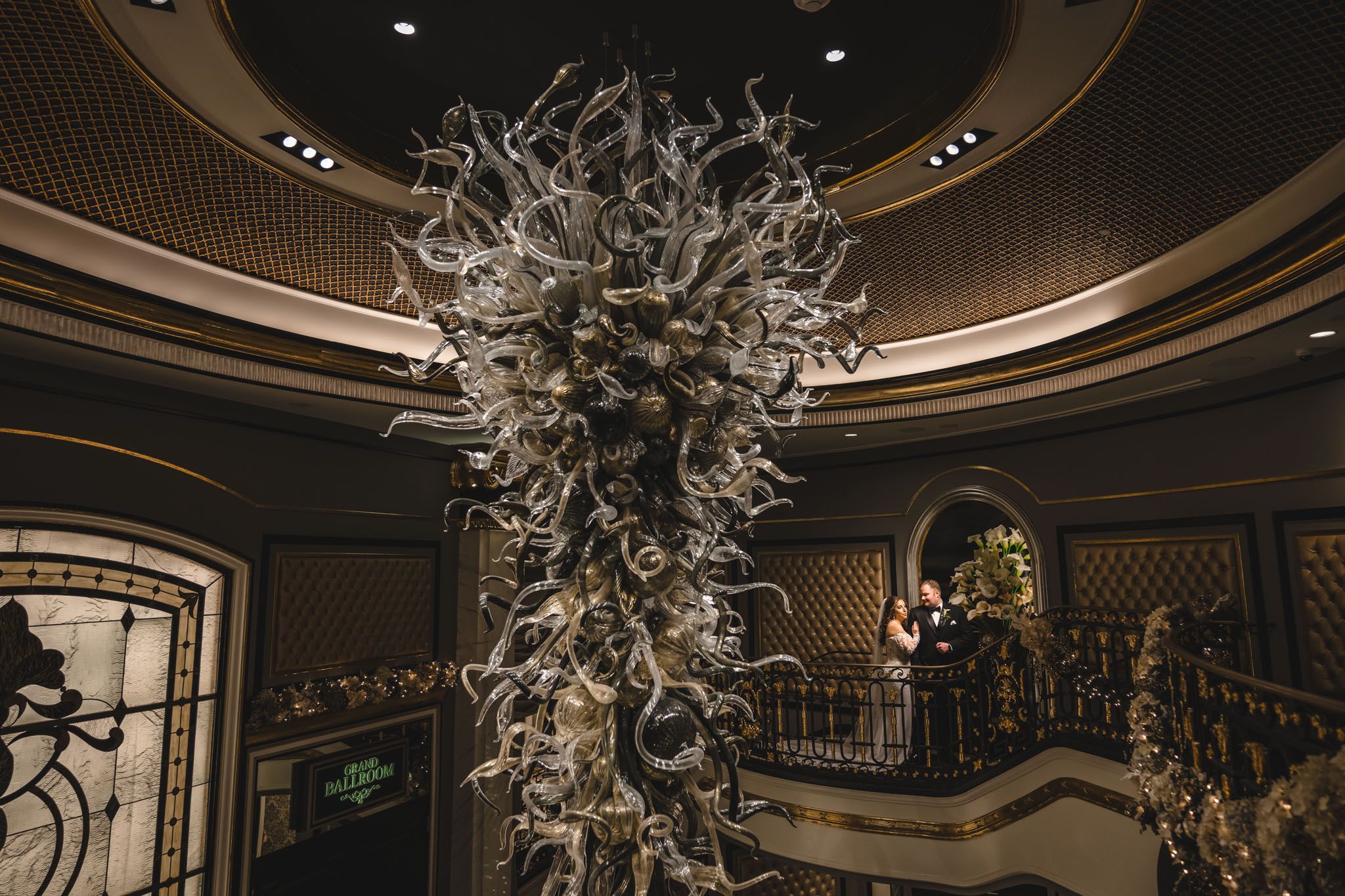 Stunning glass chandelier installation creates dramatic backdrop for wedding photography.