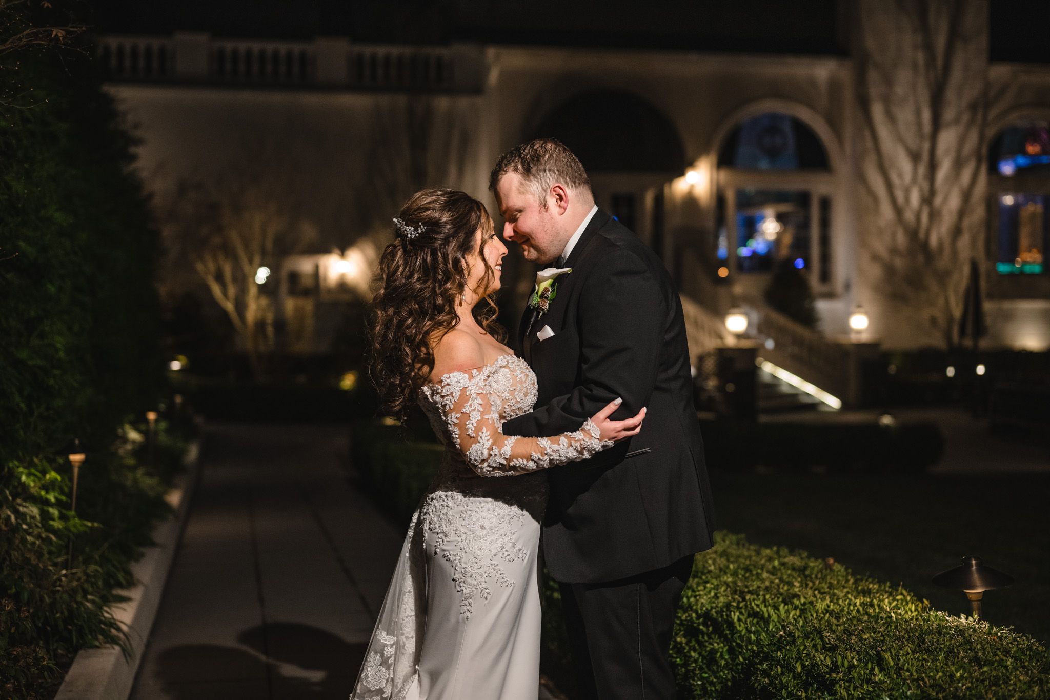 Romantic evening wedding photos captured in a garden setting with elegant lighting and formal attire.