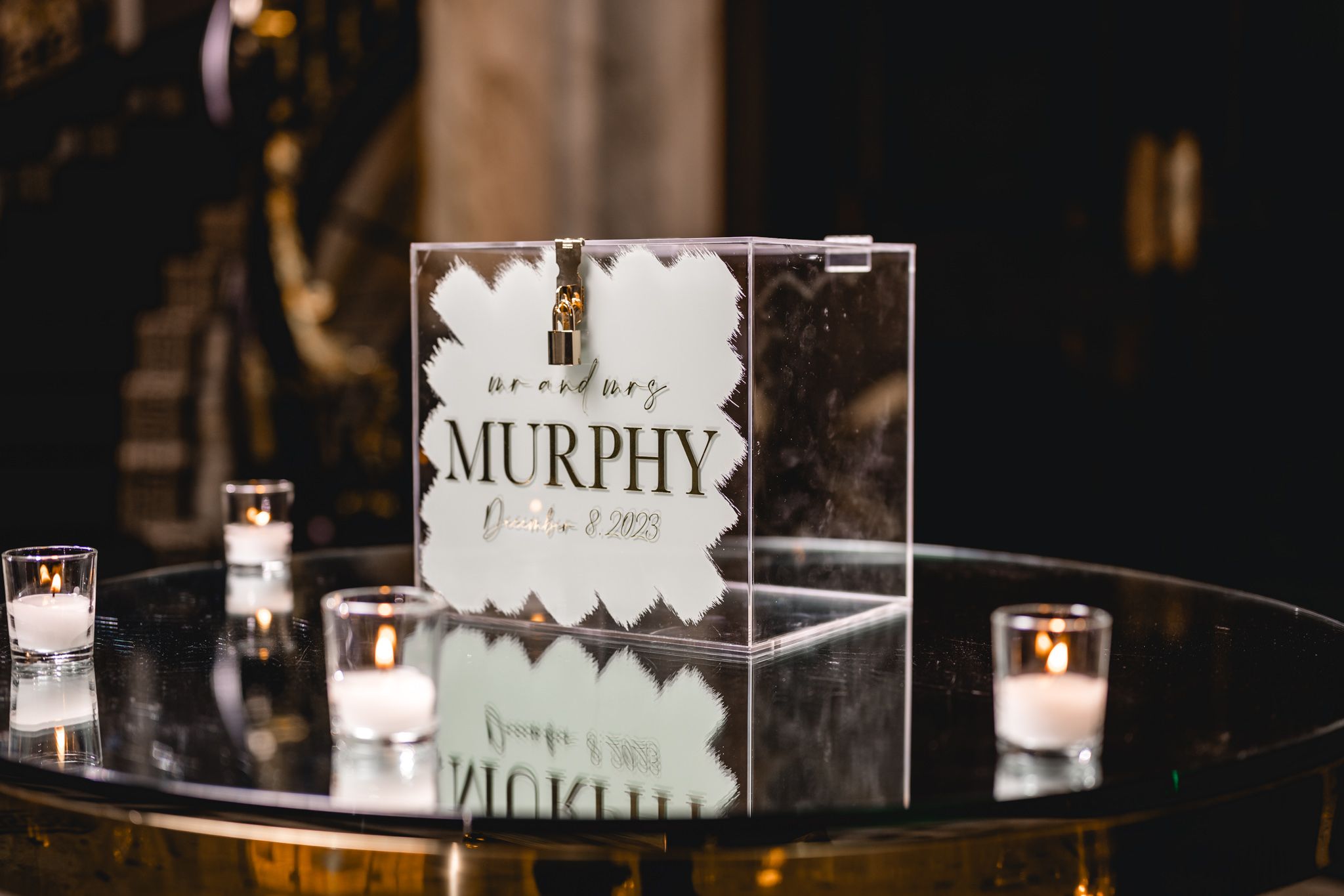 Wedding reception place cards displayed on clear acrylic stands with candlelight.
