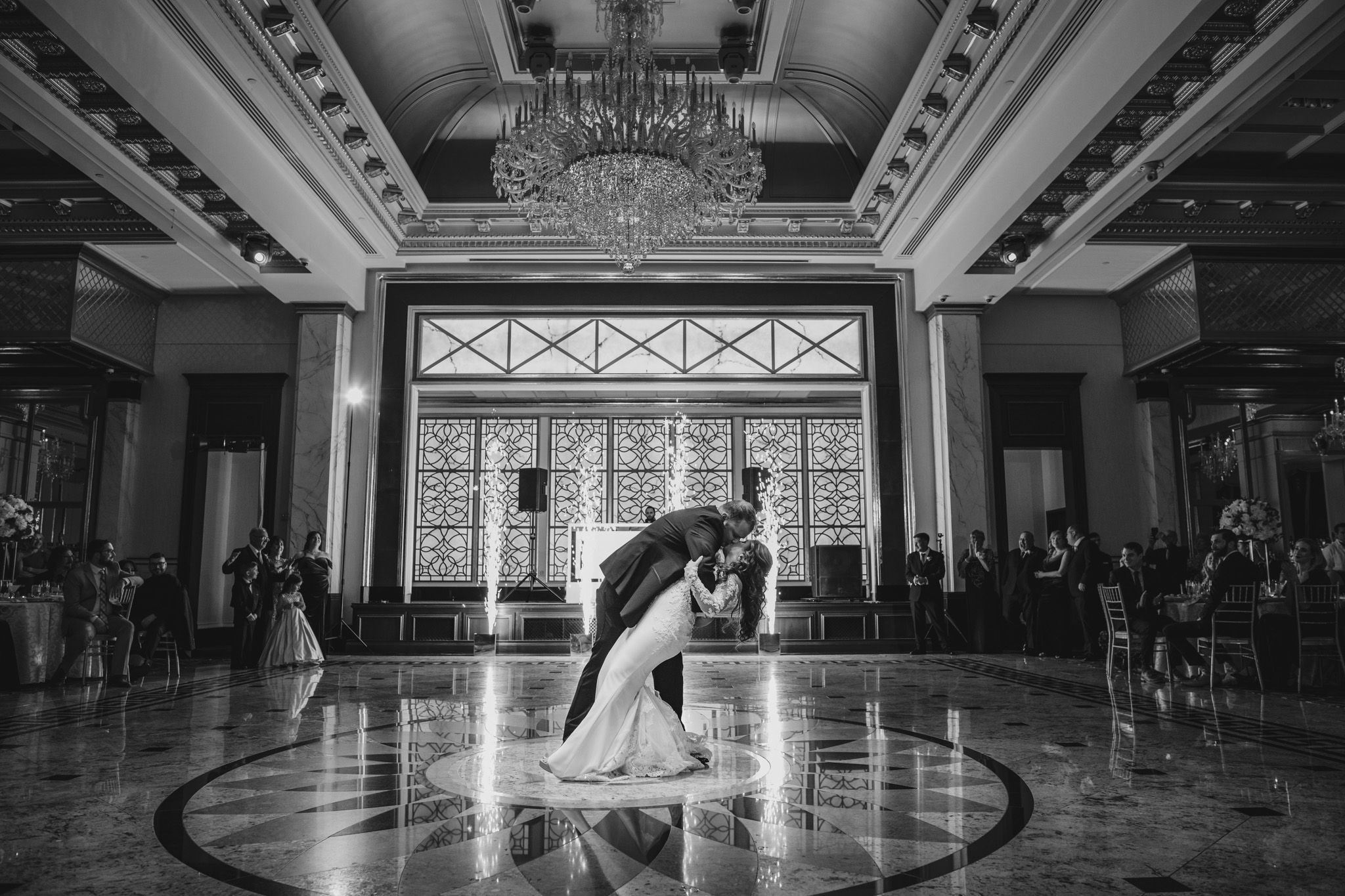 Wide view of an elegant ballroom with ornate ceiling details and dramatic lighting.